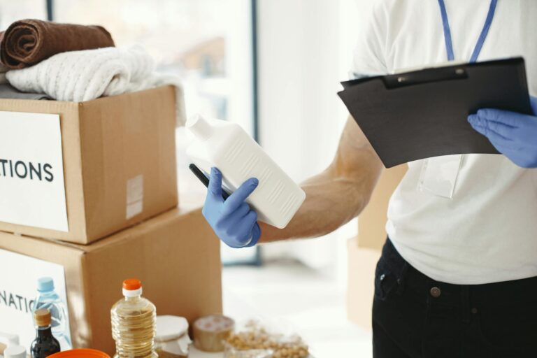 Focused volunteer in gloves sorting donation supplies in a community center.