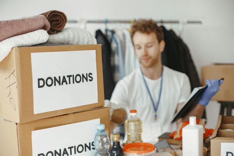 Volunteer organizing donation boxes with clothes and supplies for charity.