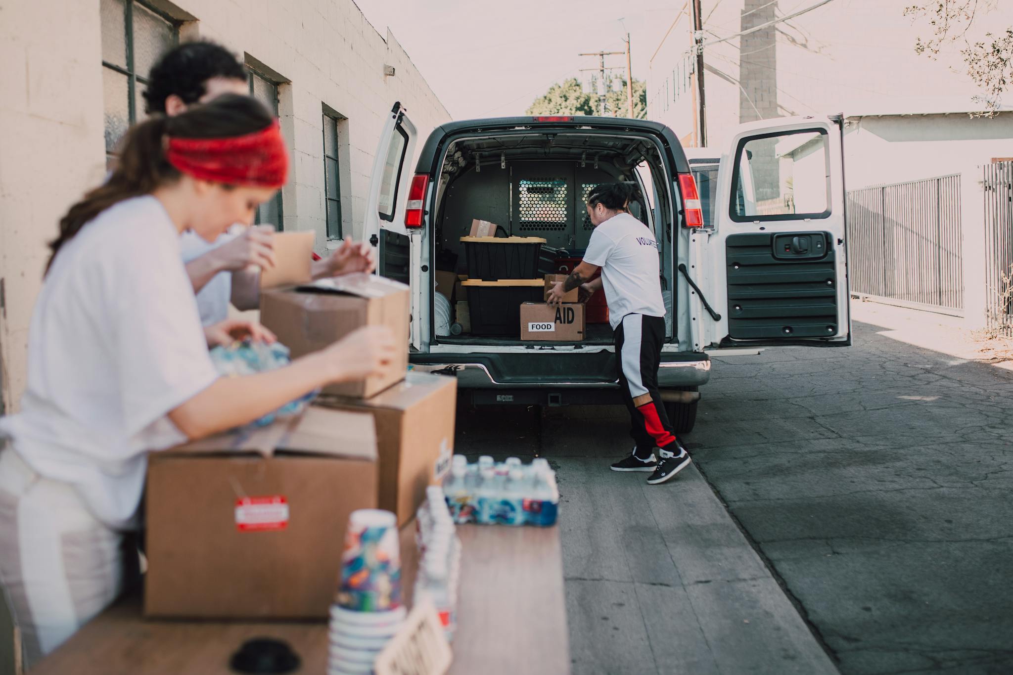 Volunteers organize and load boxes of donated supplies into a van for distribution.